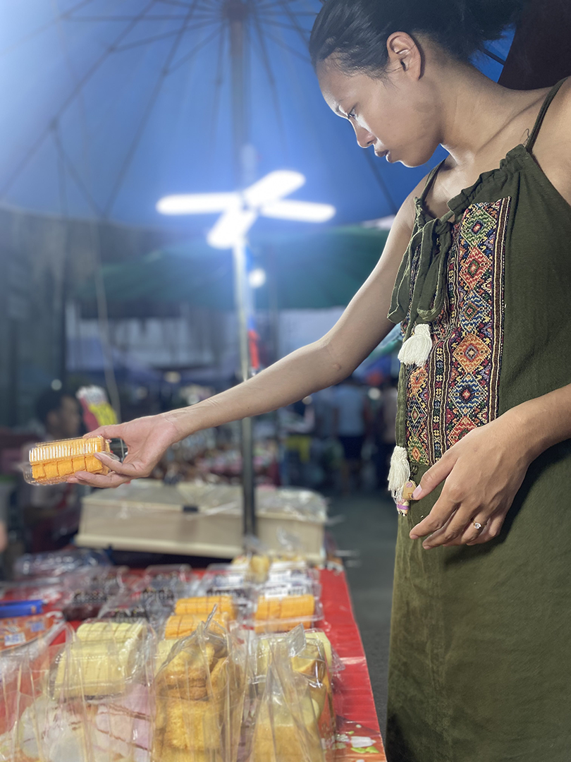 Sam's wife buying an item at the market