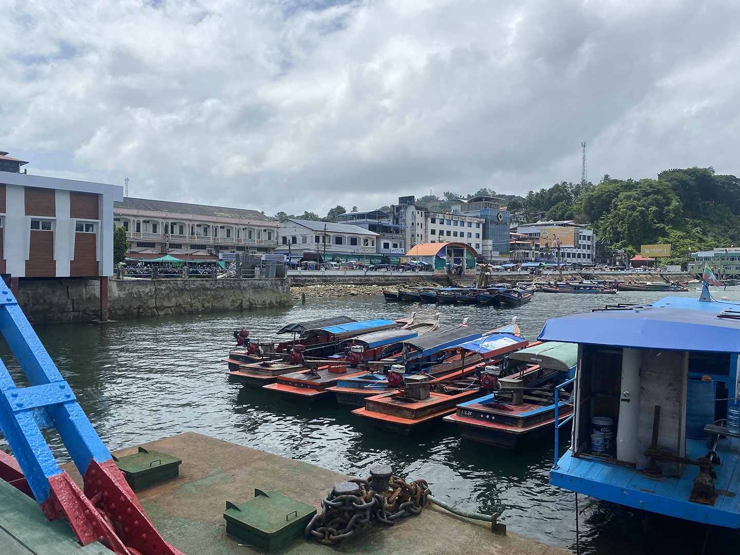 Many boats docked at a pier with building displayed behind them