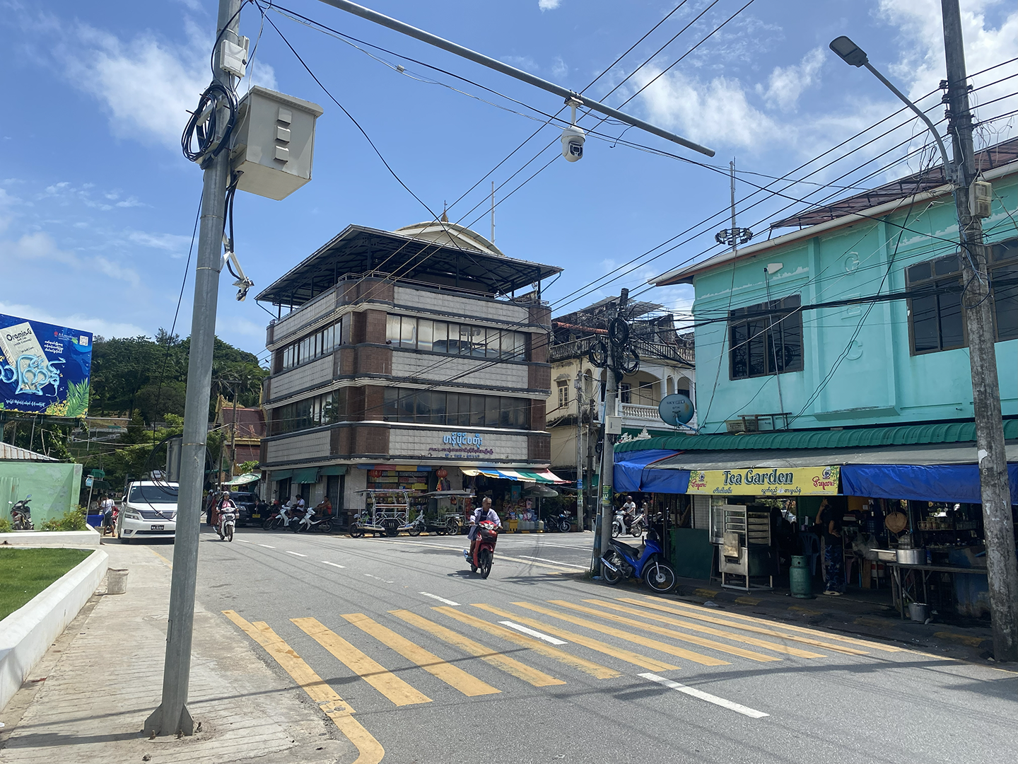 Calm street in Myanmar with normal buildings and a security camera on a street post in the middle