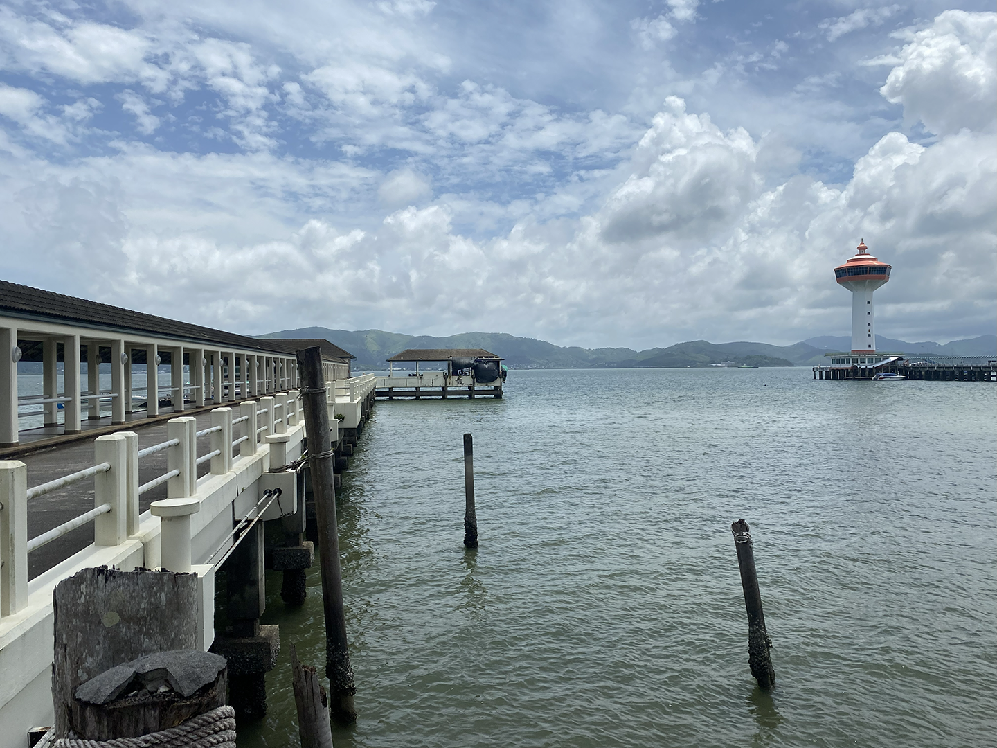 View out across Myanmar-Thailand border river with lighthouse to the right and boat dock to the left
